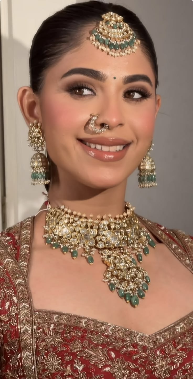 Bride smiling in red embroidery with a large gold nath