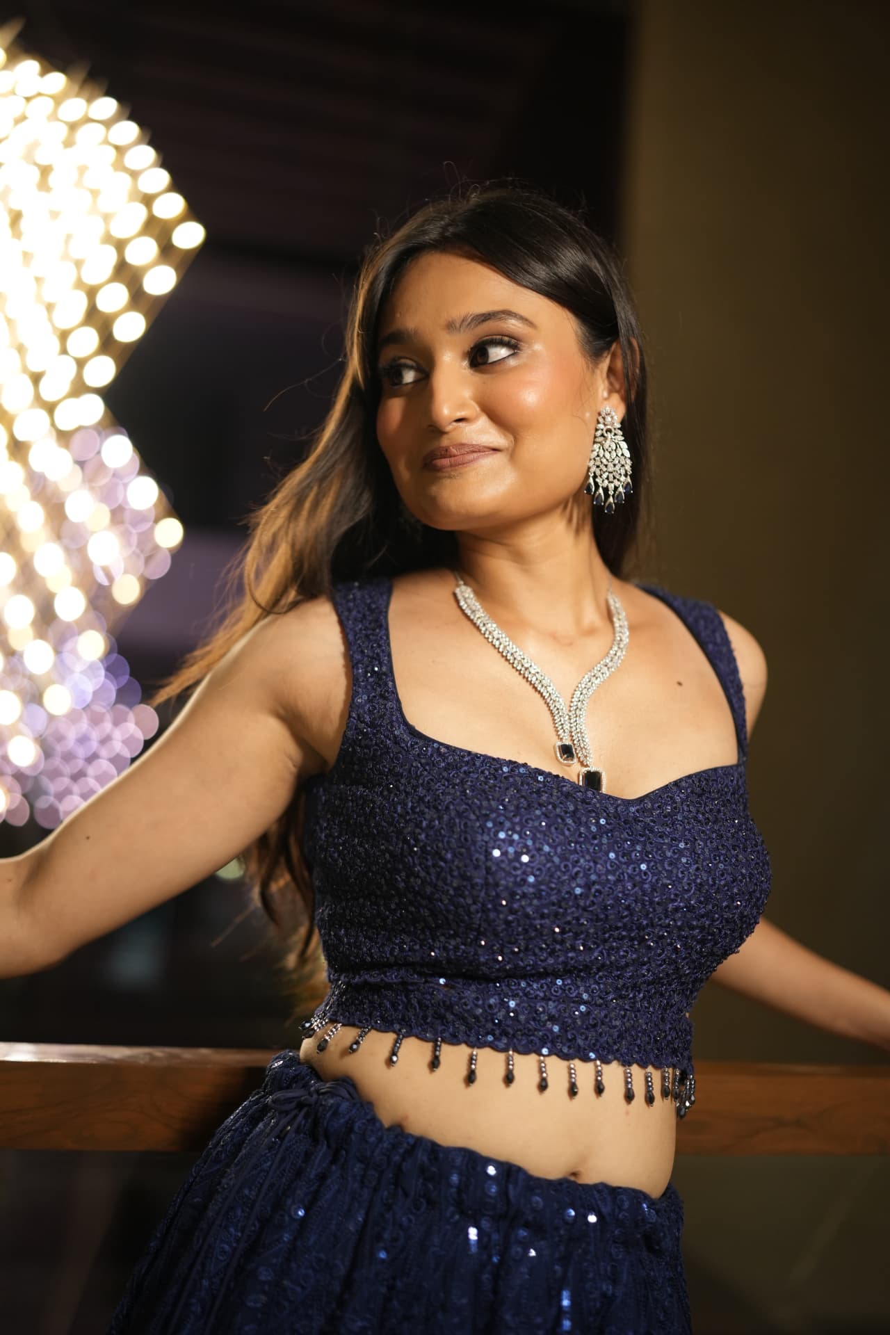 Soft glam evening look with luminous skin and diamond jewellery in warm bokeh light