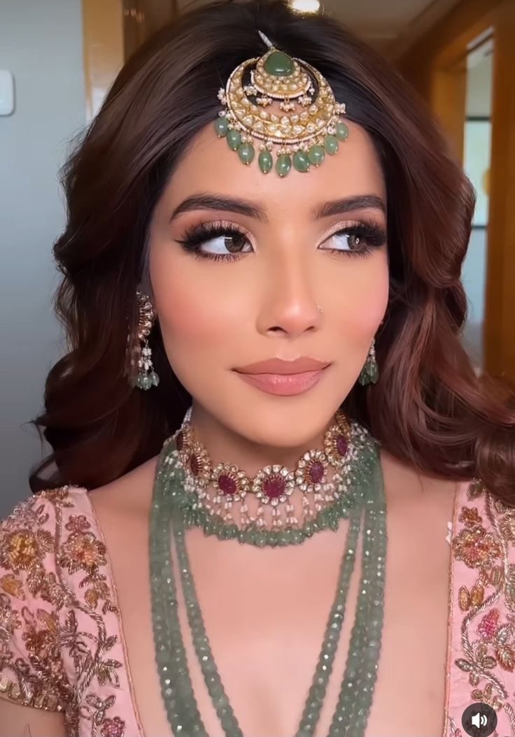 Close up bridal makeup with warm tones and an emerald maang tikka